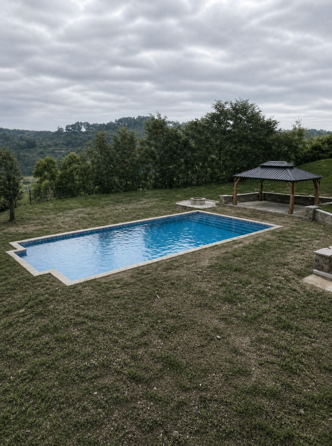 Pool surrounded by patchy worn grass before the PaverTurf installation